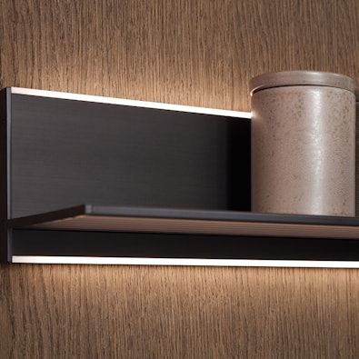 Verlichte wandplank op houtstructuur achterwand.