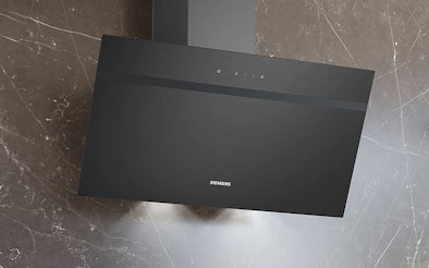 Zwarte wandschouw afzuigkap boven de kookplaat, gemonteerd aan de muur voor het afzuigen van kookdampen en geuren.