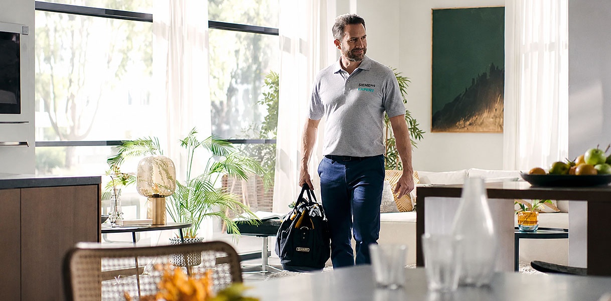 Siemens monteur met gereedschapstas loopt een woonkamer binnen om een storing te verhelpen