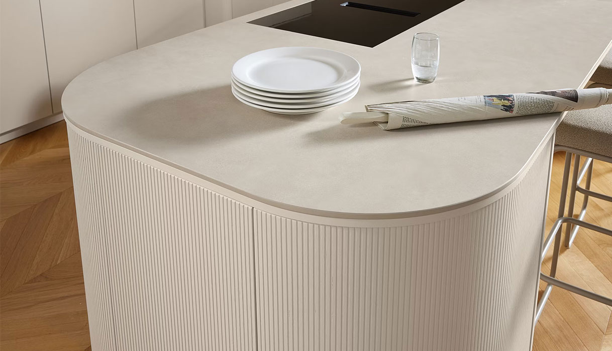 Keukeneiland in beige zandkleur met afgeronde hoeken, keramiek werkblad en verticale ribbelstructuur voor een warme en serene uitstraling.