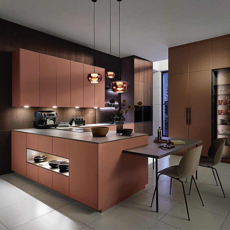 Moderne keuken met warme terracotta kleurige kasten, keukeneiland en geïntegreerd eetgedeelte met donkere houten wand