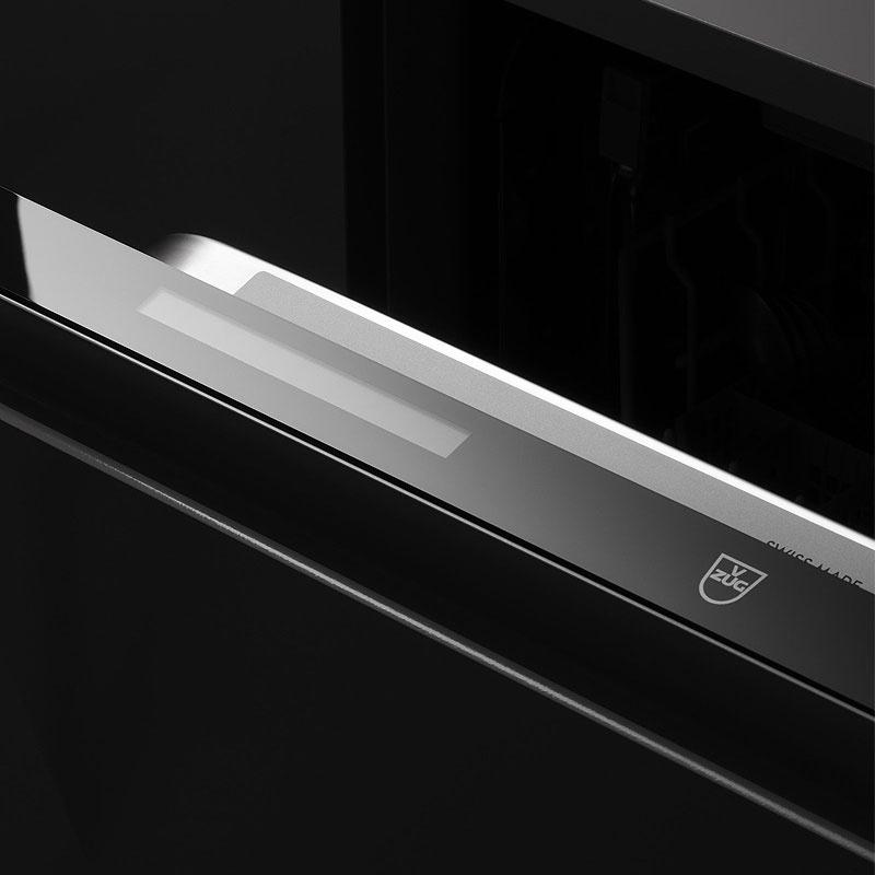 Close-up van V-ZUG Adora V6000 inbouwvaatwasser met logo; warmtepomptechnologie voor energiezuinig drogen, tot 30% minder verbruik.