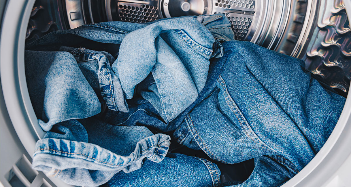 Jeans in wasdroger trommel met advies voor lage temperatuur en beperkte belading