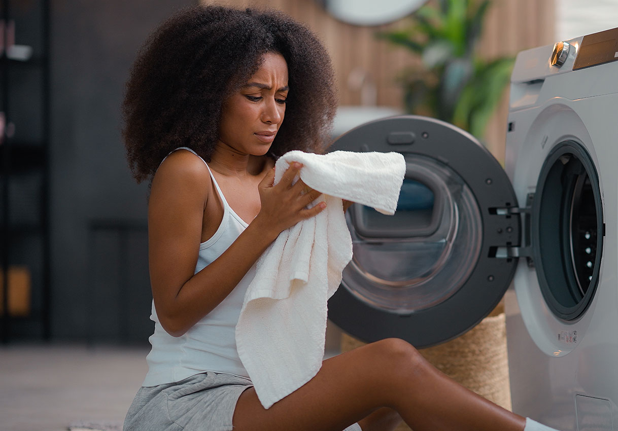 Vrouw controleert handdoek bij open wasmachine na wasbeurt met zichtbaar probleem