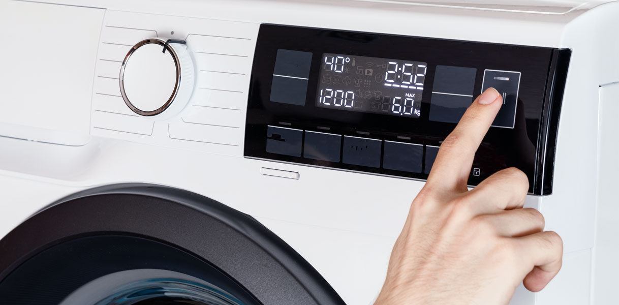 Hand bedient het digitale display van een wasmachine met instellingen voor temperatuur (40°C), toerental (1200) en programmatijd (2:52)