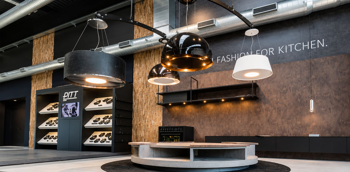 Decoratieve Wave afzuiglampen die verlichting en ventilatie combineren boven een eiland in de showroom