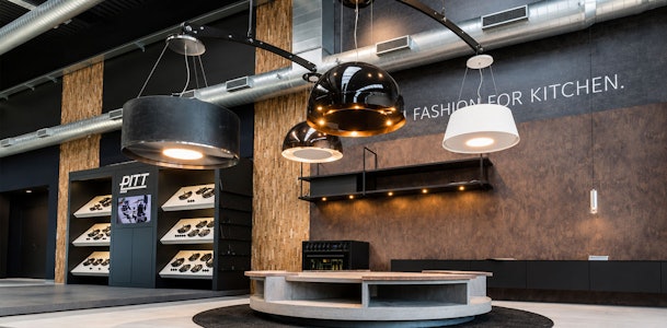 Decoratieve Wave afzuiglampen die verlichting en ventilatie combineren boven een eiland in de showroom