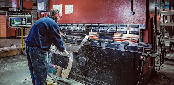Vakman buigt plaatstaal op een kantbank in de fabriek waar Wave afzuigkappen worden gemaakt