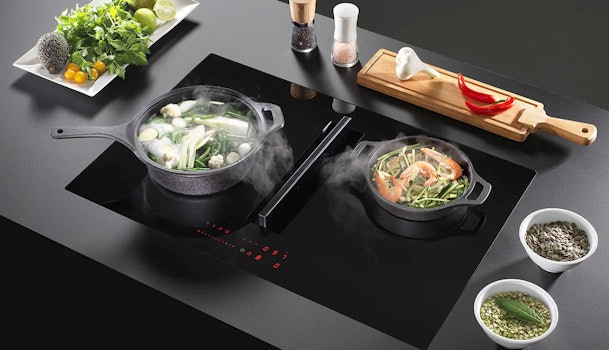 Wave inductiekookplaat met geïntegreerde afzuiging en twee pannen op een zwart werkblad.