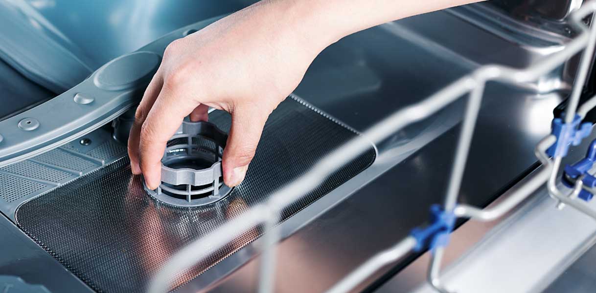 Hand verwijdert filter uit vaatwasser voor wekelijks onderhoud