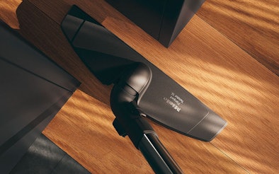 Miele steelstofzuiger met 180° draaibare zuigkop tussen meubelpoten op parket - wendbare constructie voor houten vloeren