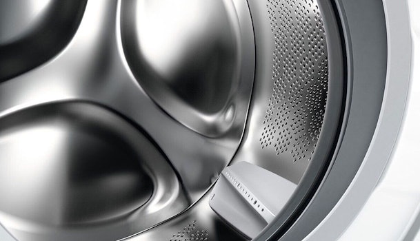 Close-up van wasmachine trommel met kleine gaatjes en afgeronde meenemers