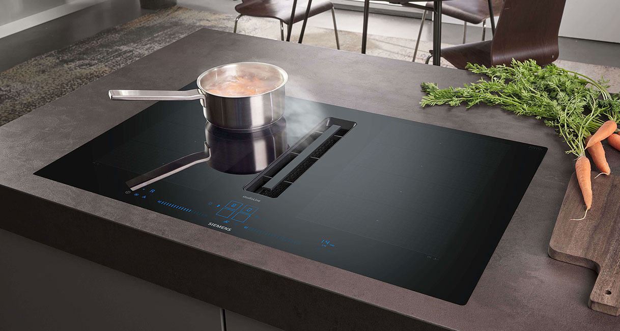 Inductie kookplaat met geïntegreerde afzuiging die stoom van een pan direct via de centrale afzuiging wegzuigt.