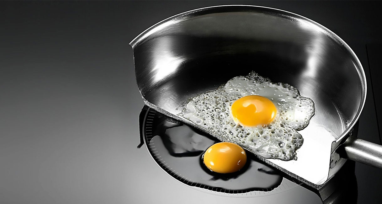 Doorsnede van een pan op een inductiekookplaat die laat zien hoe de panbodem wordt verwarmd terwijl de kookplaat koel blijft.