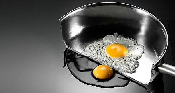 Doorsnede van een pan op een inductiekookplaat die laat zien hoe de panbodem wordt verwarmd terwijl de kookplaat koel blijft.