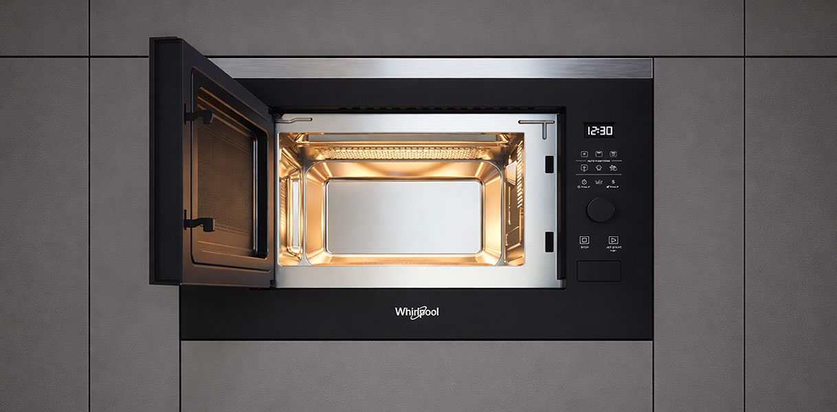 Whirlpool solo magnetron ingebouwd met open deur en verlichte binnenkant in grijze keukenkasten