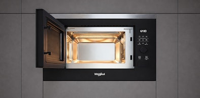 Whirlpool solo magnetron ingebouwd met open deur en verlichte binnenkant in grijze keukenkasten