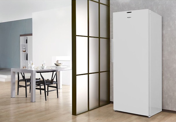 Vrijstaande Whirlpool vriezer naast een moderne eetruimte met houten vloer en glazen schuifwand