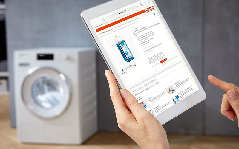 Gebruiker bedient Miele wasdroogcombinatie via tablet met WiFiConn@ct smart control app