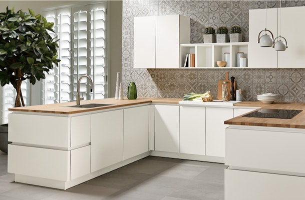 Witte U-keukenopstelling met een houten blad.