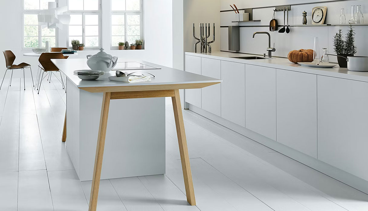 Strakke witte keuken met kookeiland, houten accenten en veel daglicht voor een frisse en ruimtelijke uitstraling.