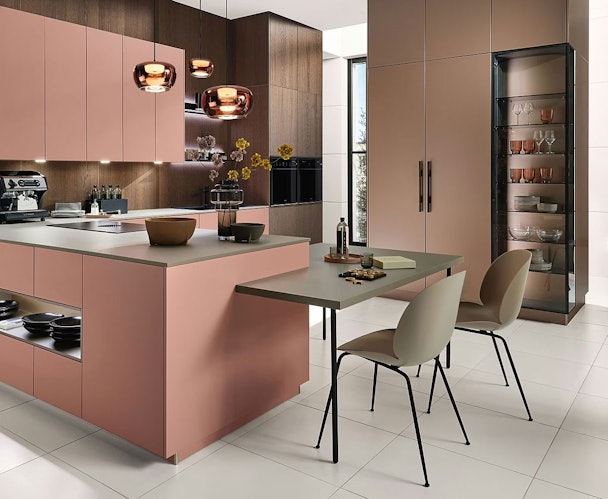 Moderne keuken met kookeiland en geïntegreerd zitgedeelte op eettafelhoogte met twee stoelen, uitgevoerd in zachte roze en houttinten