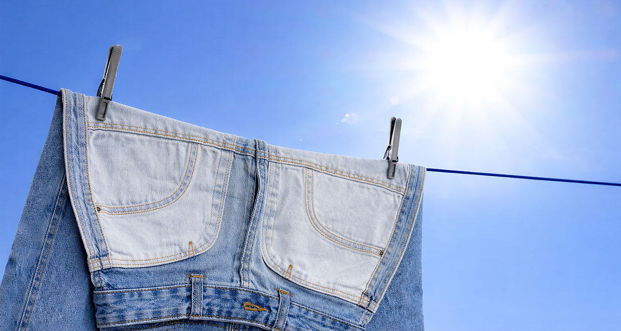 Jeans drogen aan waslijn buiten met zonlicht voor sneller drogen zonder droger