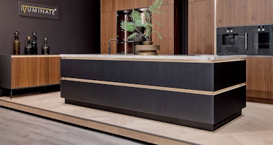 Zwart kookeiland met greeploze fronten en licht werkblad in luxe showroomkeuken