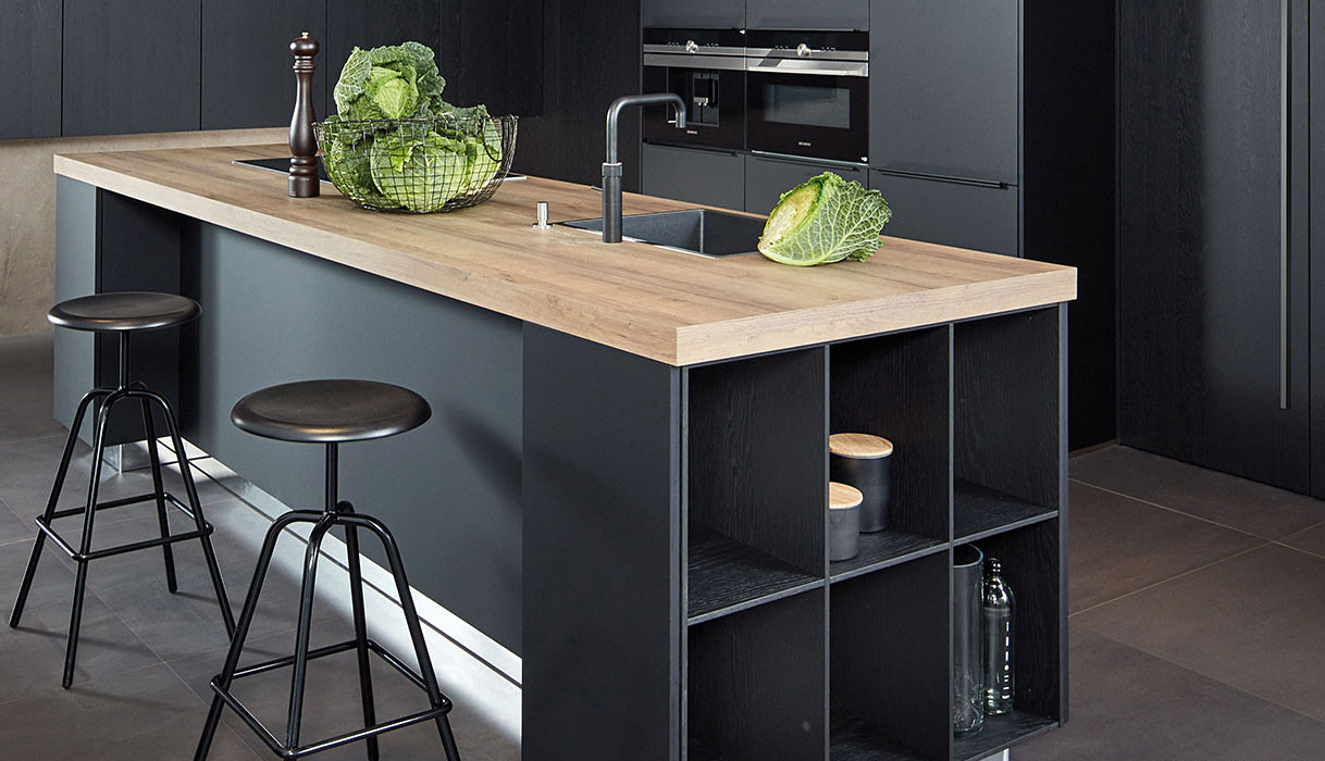 Moderne zwarte keuken met kookeiland, houten werkblad en donkere kasten voor een luxe en krachtige uitstraling.