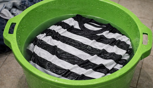 Zwart wit gestreept shirt ligt in een wasmand met water om te testen op kleurafgifte