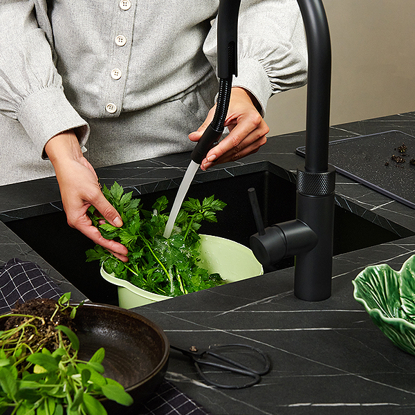Zwarte Quooker Flex met uittrekslang boven zwarte granieten spoelbak