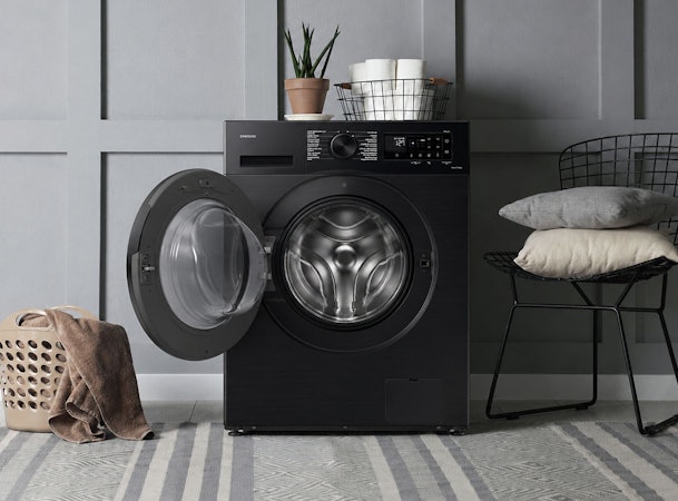 Zwarte voorlader wasmachine in moderne wasruimte met open deur en stijlvolle matte afwerking.