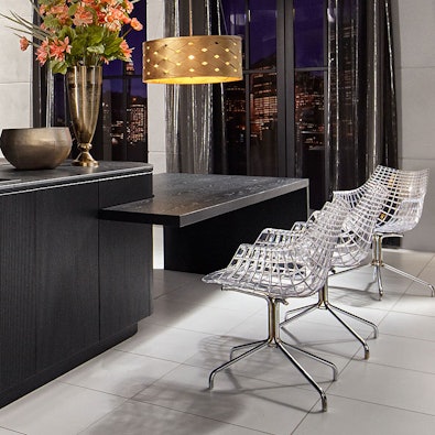 Verlengd donker blad als bargedeelte met drie transparante stoelen.